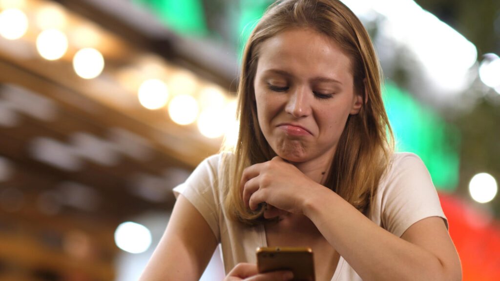 Woman staring at her phone looking unhappy